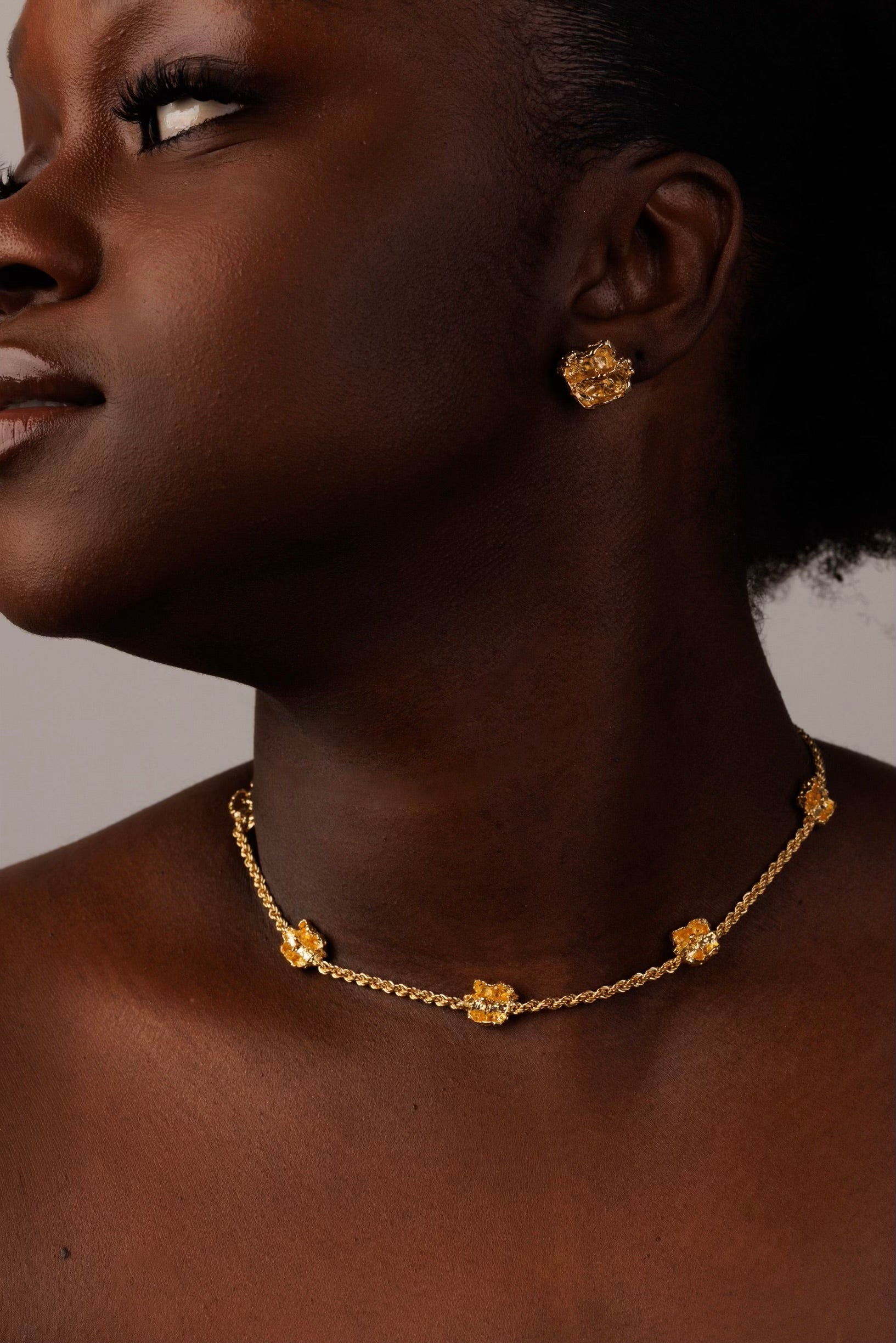 Woman wearing gold jewelry with a neutral background