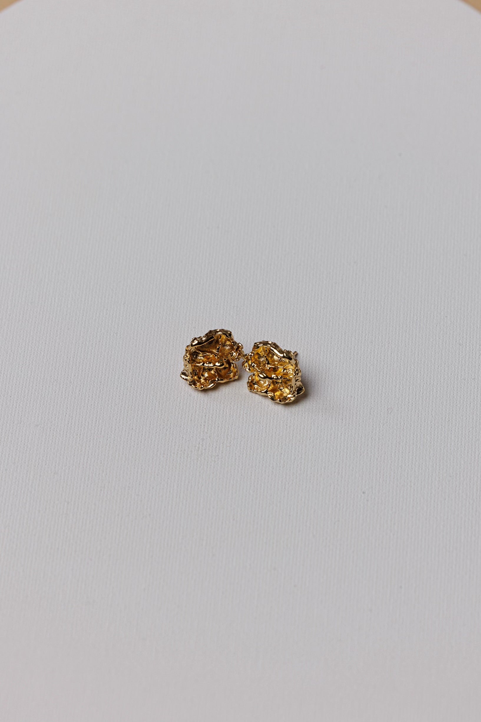 Pair of gold earrings on a light gray background
