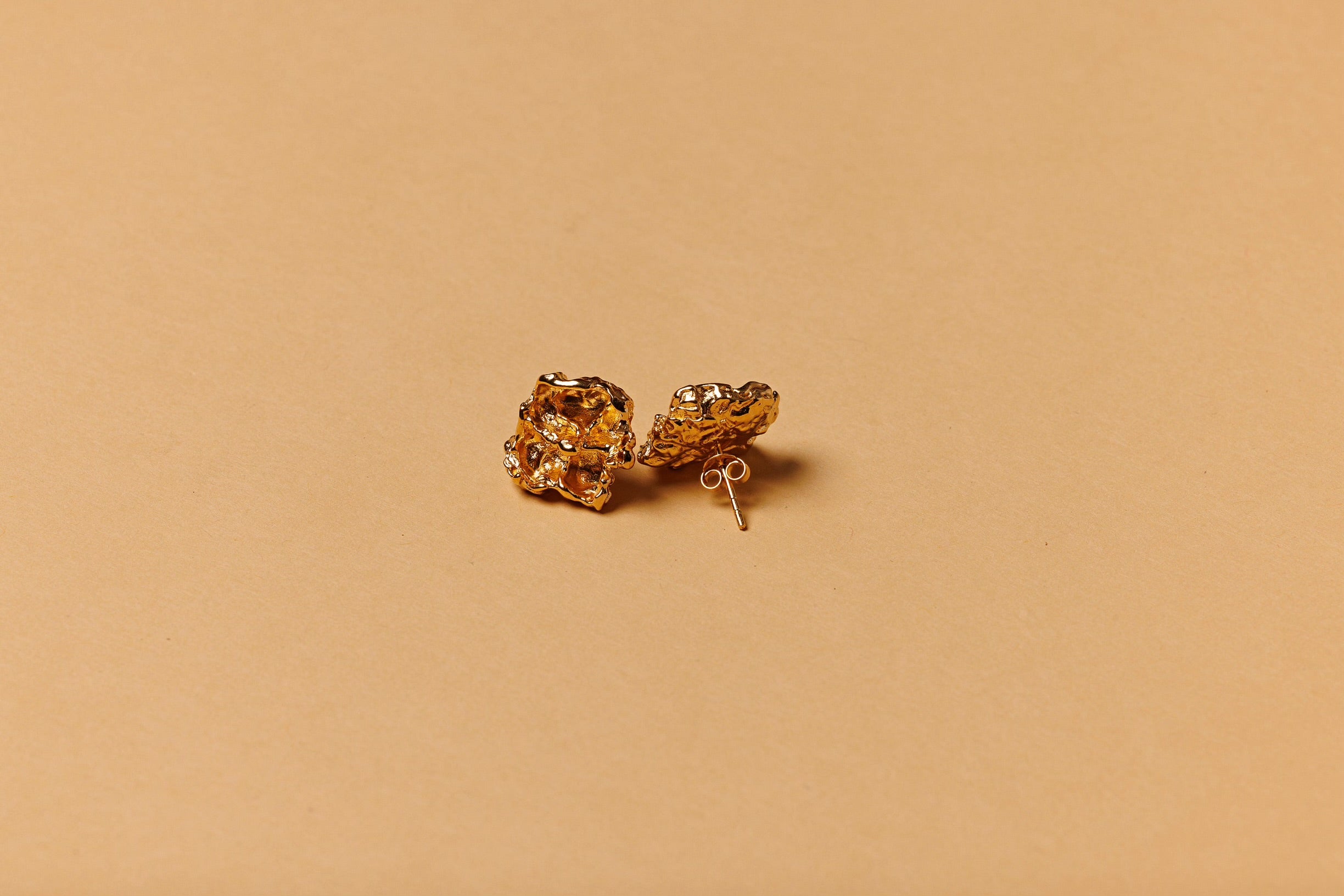 Gold earrings on a beige background