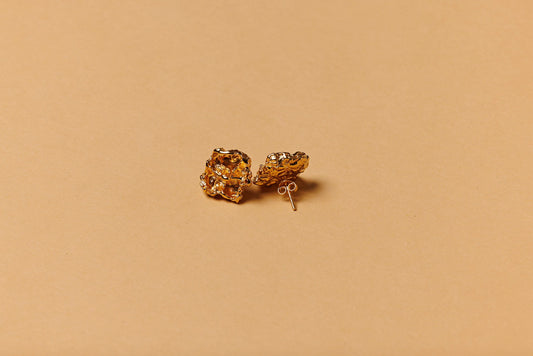 Gold earrings on a beige background