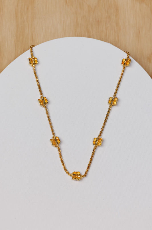 Gold necklace on a white pedestal with a wooden background